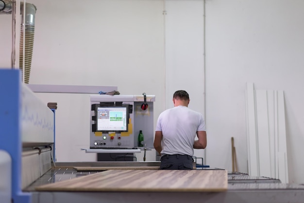 Jovem trabalhador trabalha em uma fábrica para a produção de móveis de madeira