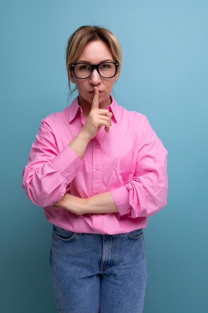 Jovem trabalhadora de escritório europeia inteligente vestida com uma camisa rosa e óculos mantém um segredo