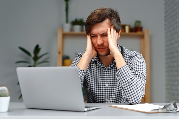 Jovem trabalhando em um laptop em sua mesa de trabalho de perto