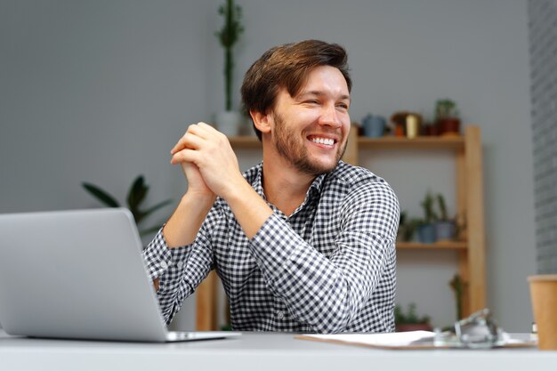 Foto jovem trabalhando em um laptop em sua mesa de trabalho