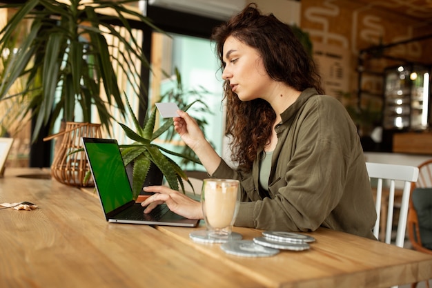 Jovem trabalhando em uma cafeteria com uma freelancer mulher laptop segurando um cartão de crédito