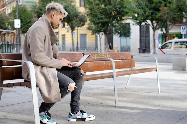 Jovem trabalhando mais feliz com seu laptop na rua