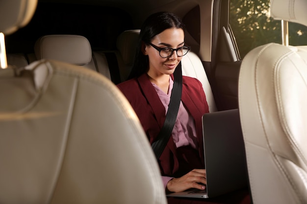 Jovem trabalhando no laptop em táxi moderno