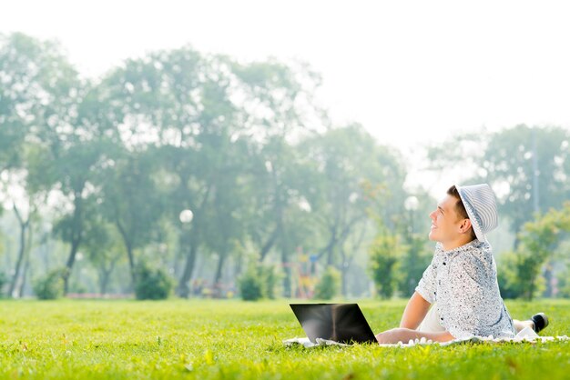 Jovem trabalhando no parque com um laptop