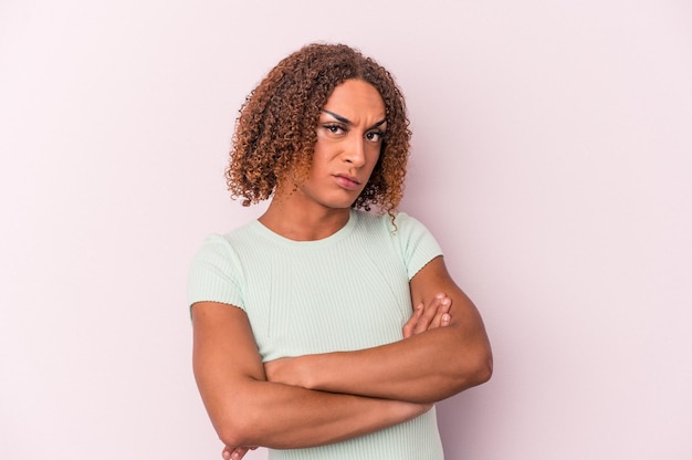 Jovem transexual latina isolada em fundo rosa suspeito, incerto, examinando você.