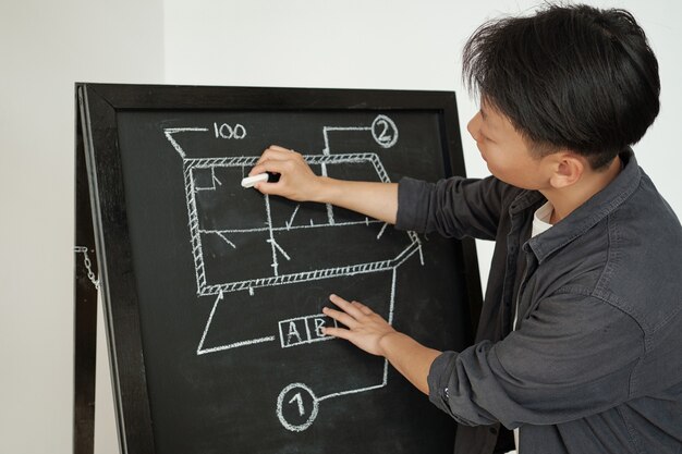 Foto jovem treinador de engenharia desenhando esboço no quadro-negro durante a apresentação do projeto em seminário ou conferência