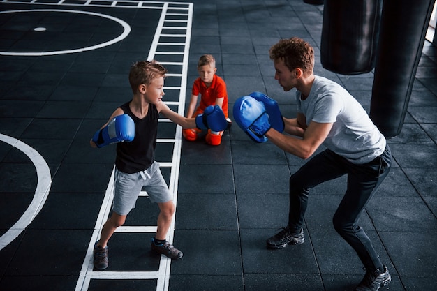 Jovem treinador ensina às crianças boxe desportivo no ginásio.