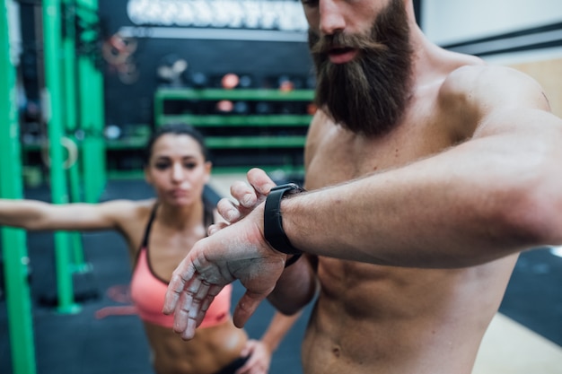 Jovem treinador esportivo ginásio indoor usando smartwatch