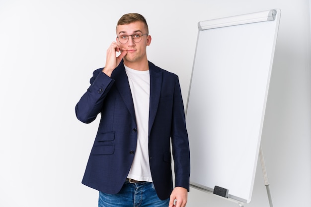 Foto jovem treinando homem mostrando um quadro branco com os dedos nos lábios, mantendo um segredo.