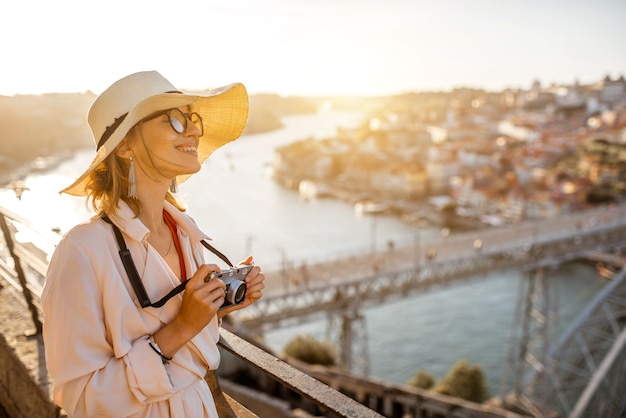 Foto jovem turista apreciando a bela vista aérea da cidade com a famosa ponte durante o pôr do sol na cidade do porto, portugal