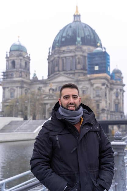 Jovem turista barbudo feliz tendo sua foto tirada com a Catedral de Berlim ao fundo