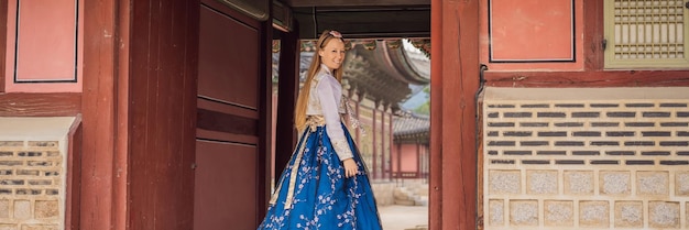 Jovem turista caucasiana em vestido coreano nacional hanbok Conceito de viagem para a Coreia Roupas coreanas nacionais Entretenimento para turistas experimentando roupas coreanas nacionais BANNER LONG FORMAT