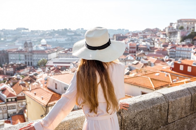 Jovem turista com chapéu em pé no fundo da cidade velha, viajando pela cidade do Porto, Portugal