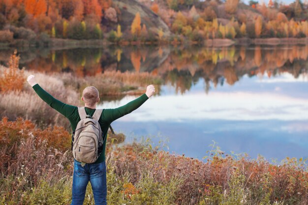 Foto jovem turista com mochila perto do lago de outono