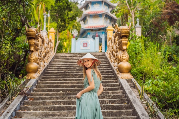 Foto jovem turista com um chapéu tradicional vietnamita viaja para o vietnã