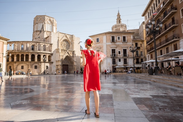 Jovem turista com um vestido vermelho em pé na praça central da cidade de Valência, Espanha