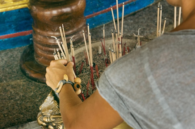 Jovem turista demale colocando vara fumegante dentro do incensário no templo