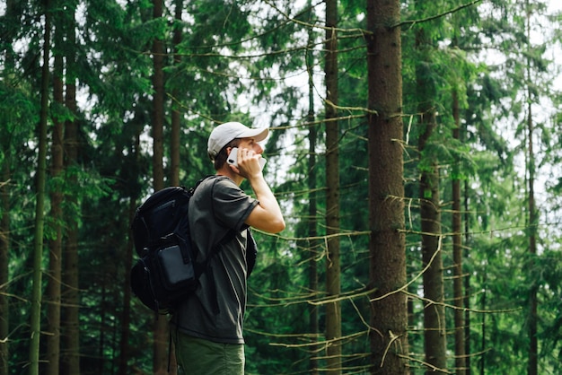 Jovem turista em roupas confortáveis e com uma mochila fica em uma floresta de montanha