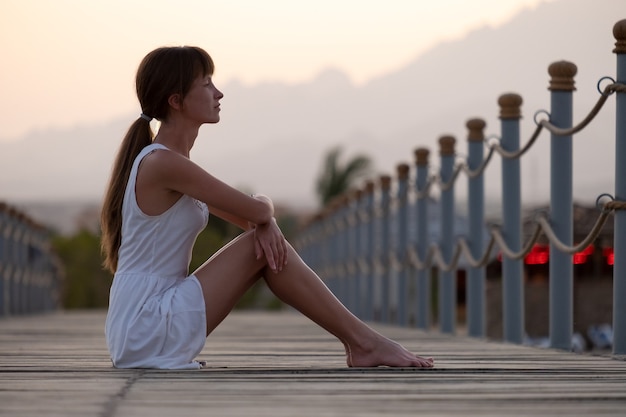 Jovem turista feminina em roupas casuais, aproveitando a noite de sol quente na costa do mar. Férias de verão e conceito de viagem.