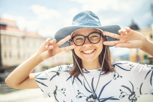 Jovem turista feminina feliz usando óculos e um chapéu, mostrando uma expressão legal na praça da cidade.