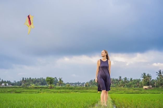 Jovem turista lança uma pipa em um campo de arroz na ilha de ubud bali indonésia