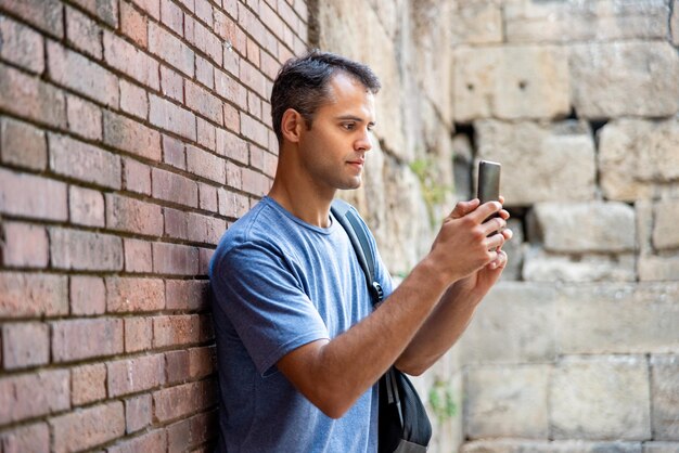 Jovem turista latino com telemóvel lá fora.