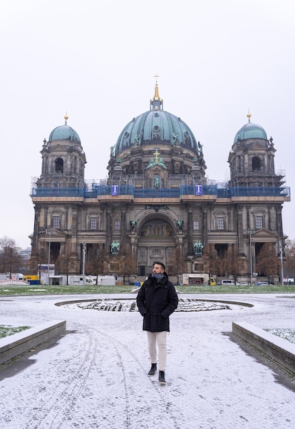 Jovem turista masculino andando no parque em frente à Catedral de Berlim com neve por todo o chão