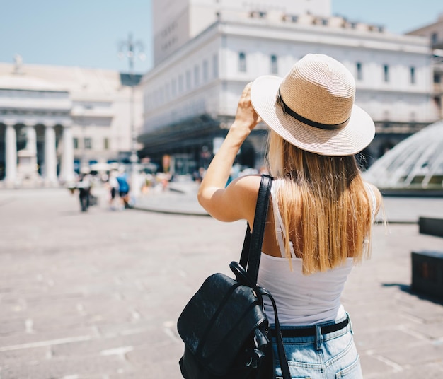 Jovem turista sorridente atraente de chapéu explorando a nova cidade da europa nas férias de verão