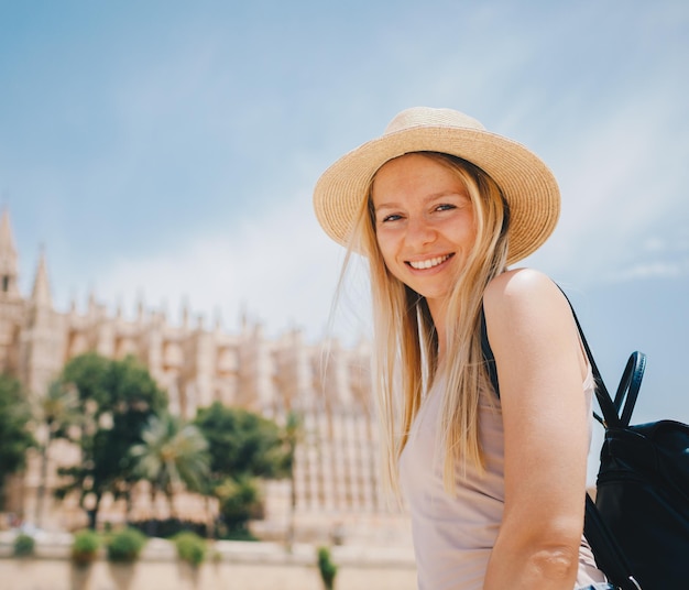 Jovem turista sorridente atraente de chapéu explorando a nova cidade da europa nas férias de verão