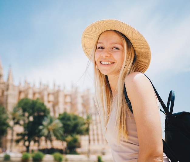 Jovem turista sorridente atraente de chapéu explorando a nova cidade da Europa nas férias de verão