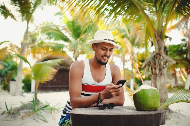 Jovem turista sorrindo enquanto verifica o smartphone durante as férias na ilha