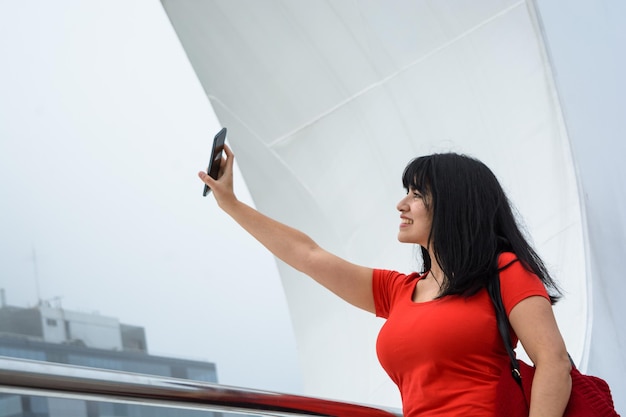 Jovem turista tirando uma foto de selfie com seu telefone ao ar livre andando pela Argentina