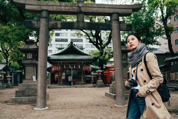 jovem turista visitando o xintoísmo japonês nas férias de primavera. lanternas de pedra torii e toro em segundo plano em tenmangu. pessoas rezando enfeitando no conceito de estilo de vida do santuário.