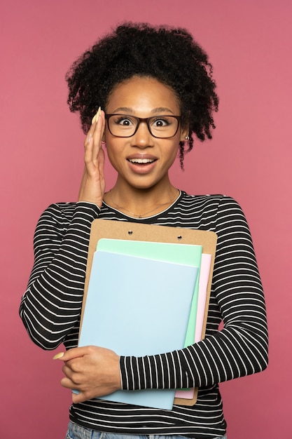 Jovem tutora afro-americana feliz ou professora isolada em uma parede rosa