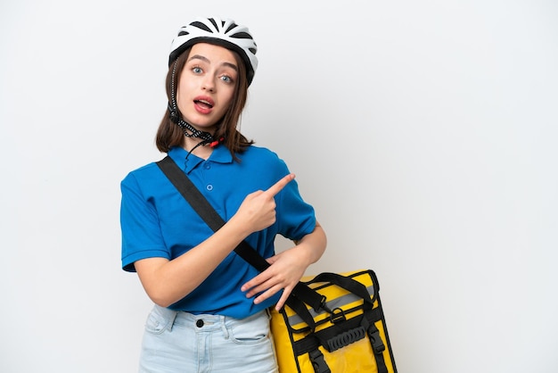 Jovem ucraniana com mochila térmica isolada em fundo branco surpreso e apontando o lado