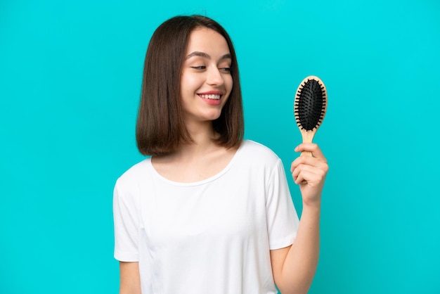 Jovem ucraniana com pente de cabelo isolado em fundo azul com expressão feliz