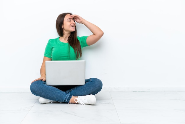 Jovem ucraniana com um laptop sentado no chão sorrindo muito