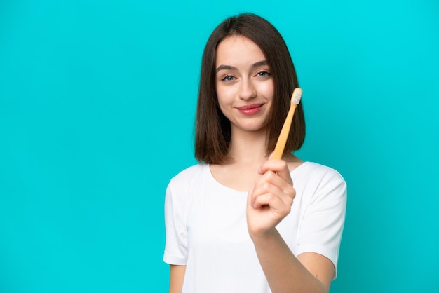 Jovem ucraniana escovando os dentes isolados em fundo azul com expressão feliz