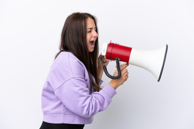 Jovem ucraniana isolada em fundo branco gritando através de um megafone para anunciar algo em posição lateral