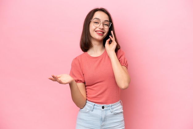 Jovem ucraniana isolada em fundo rosa, mantendo uma conversa com o celular com alguém