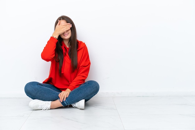 Jovem ucraniana sentada no chão isolada em fundo branco cobrindo os olhos com as mãos Não quer ver algo