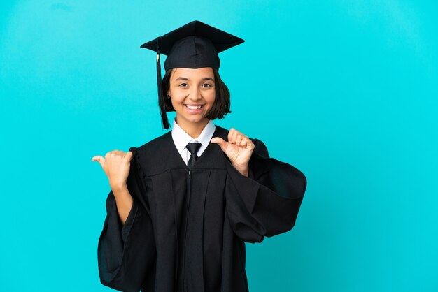 Jovem universitária com um fundo azul isolado apontando para o lado para apresentar um produto