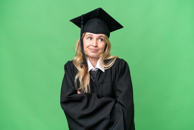 Jovem universitária inglesa graduada sobre fundo isolado fazendo gesto de dúvidas enquanto levanta os ombros