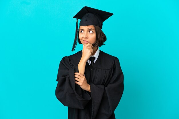 Jovem universitária sobre uma parede azul isolada, tendo dúvidas e com uma expressão confusa no rosto