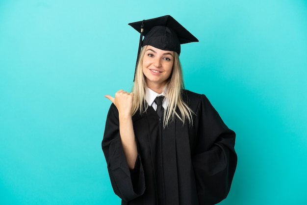 Jovem universitário com fundo azul isolado apontando para o lado para apresentar um produto