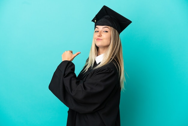 Jovem universitário sobre fundo azul isolado, orgulhoso e satisfeito