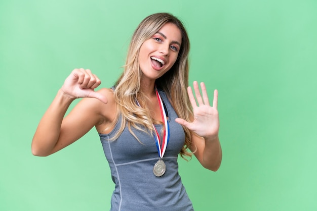 Jovem uruguaia bonita esporte com medalhas sobre fundo isolado, contando seis com os dedos