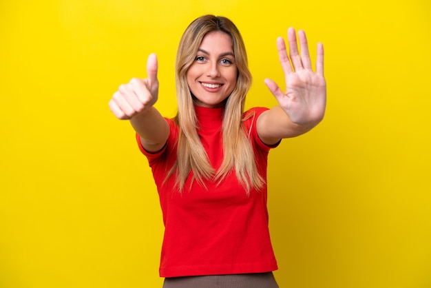 Jovem uruguaia isolada em fundo amarelo contando seis com os dedos