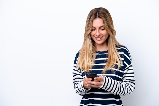 Jovem uruguaia isolada em fundo branco enviando uma mensagem com o celular