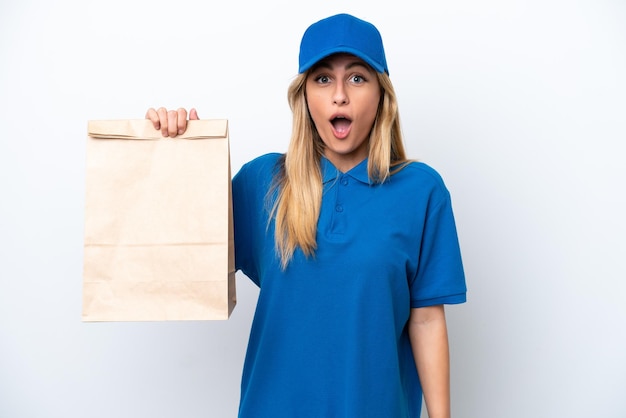 Jovem uruguaia levando um saco de comida para viagem isolada no fundo branco com expressão facial de surpresa